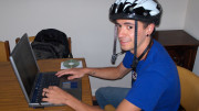 En man som surfar på internet iklädd cykelhjälm